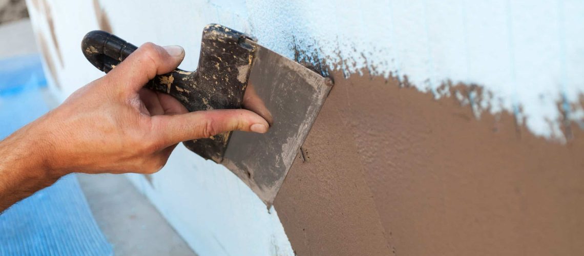 Man hand with trowel plastering a wall. Construction new frame house